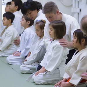 Children and instructors kneeling in calm meditation during kids martial arts class Eugene Oregon